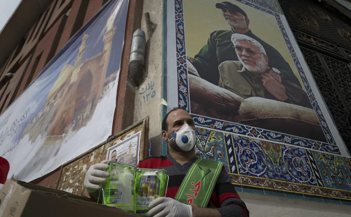 Helfer im Iran, der Autos wegen des Coronavirus desinfiziert