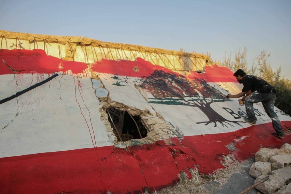 In syrischen Idlib malt ein Künstler als Zeichen der Solidarität eine libanesische Flagge auf die Ruinen eine Hauses. (imago images/ZUMA Wire)