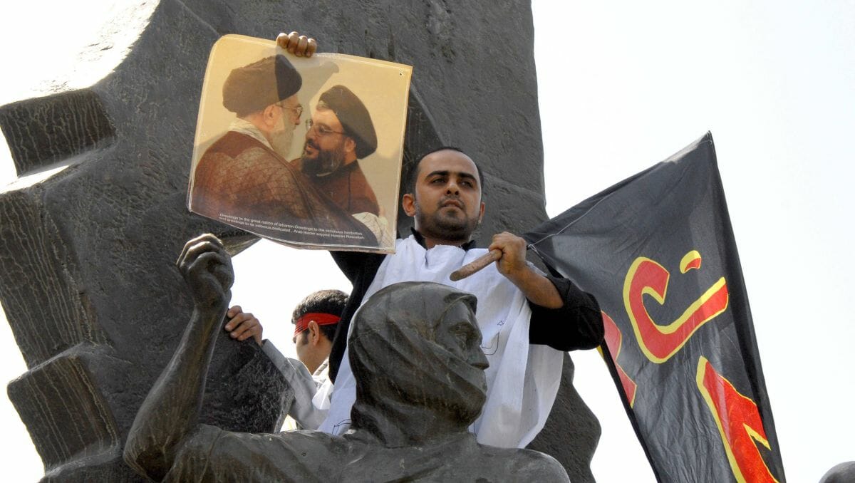 Demonstrant im Iran mit Foto von Khamenei und Nasrallah