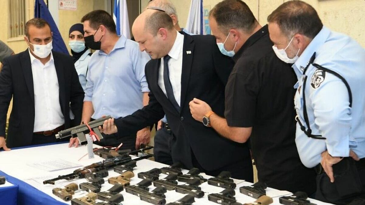 Premier Bennet betrachtet im Rahmen der "Operation Sword Strike" konfiszierte Waffen