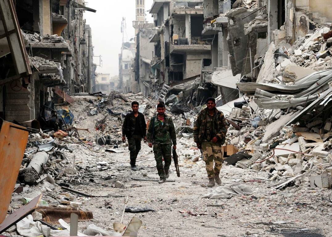 Regimetreue Soldaten in Hadschar al-Aswad nach der Rückeroberung. Die Ruinen der Stadt dienen jetzt als Kulissen für einen chinesischen Actionfilm. (© imago images/Xinhua)