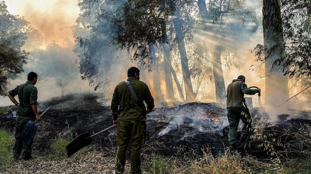 Mittlieder einer Einsatztruppe der israelischen Feuerwehr bei der Bekämpfung eines durch Hisbollah-Raketen verursachten Waldbrandes