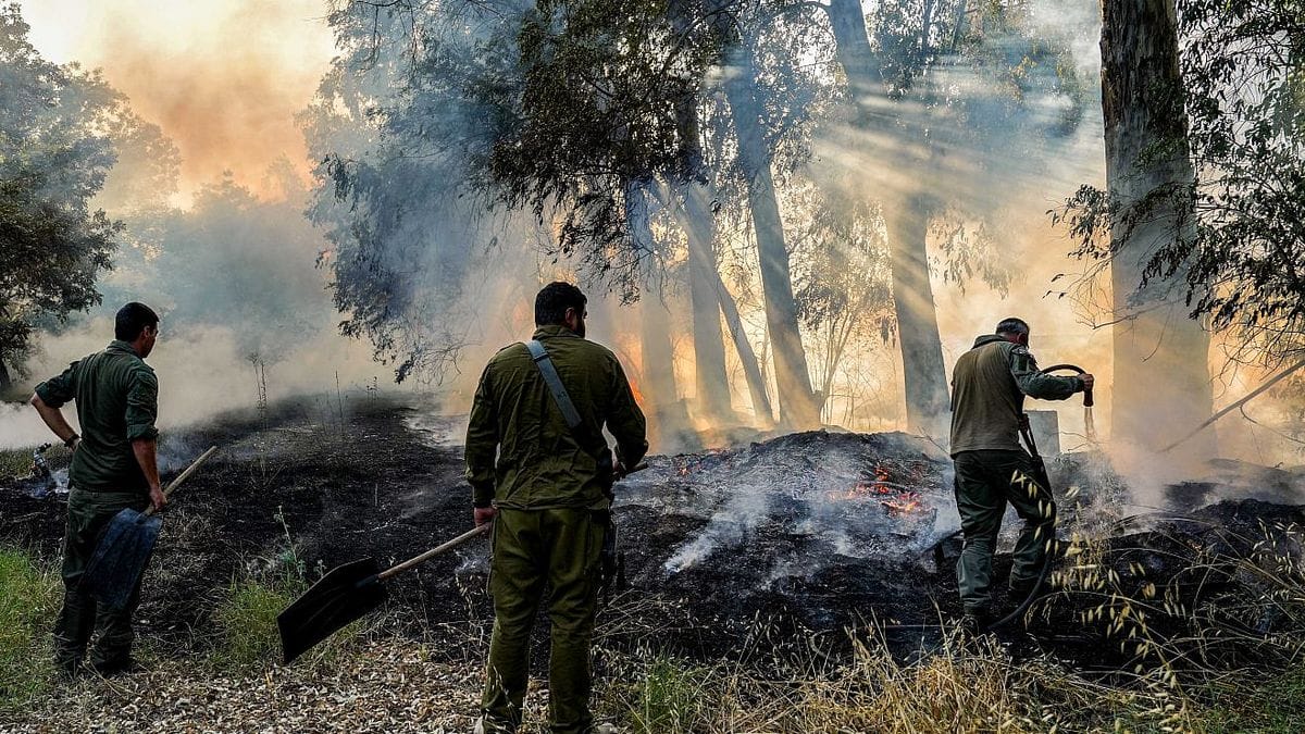 Mittlieder einer Einsatztruppe der israelischen Feuerwehr bei der Bekämpfung eines durch Hisbollah-Raketen verursachten Waldbrandes