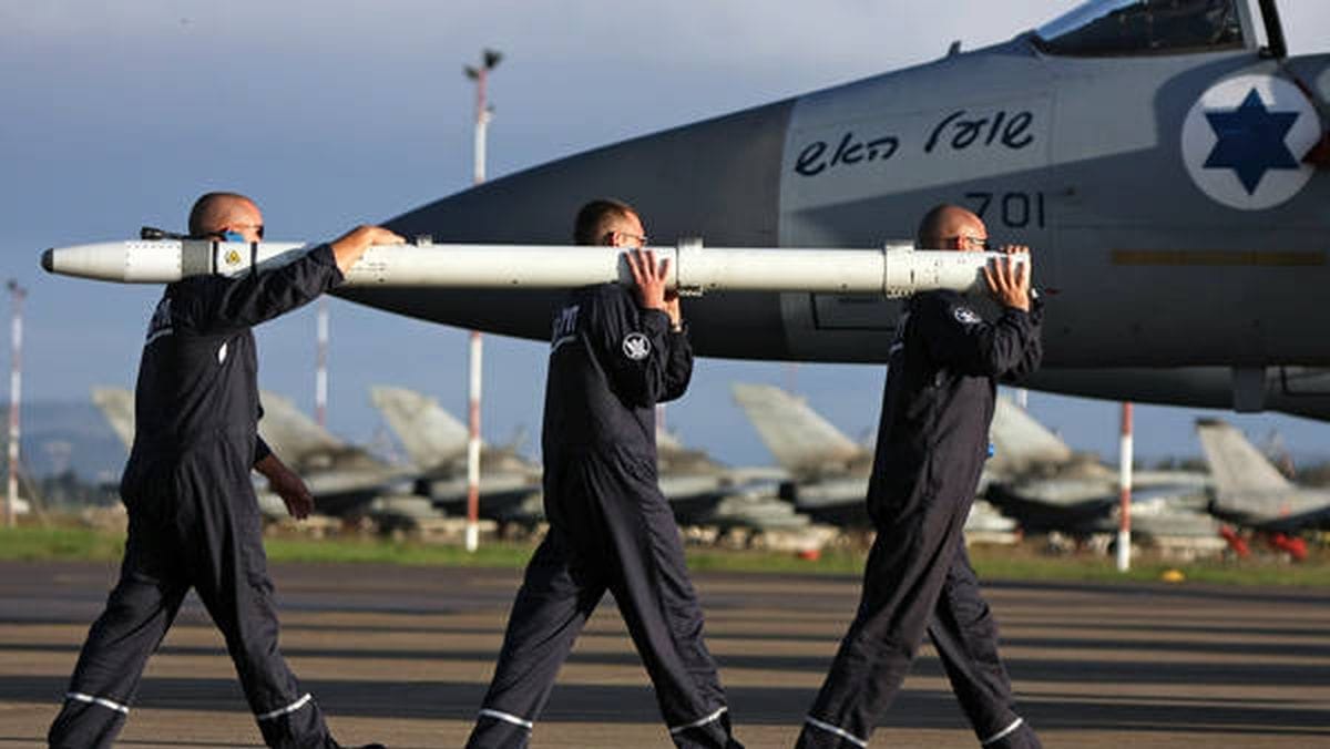 Soldaten der israelischen Luftwaffen beladen ein Kampfflugzeug mit Raketen