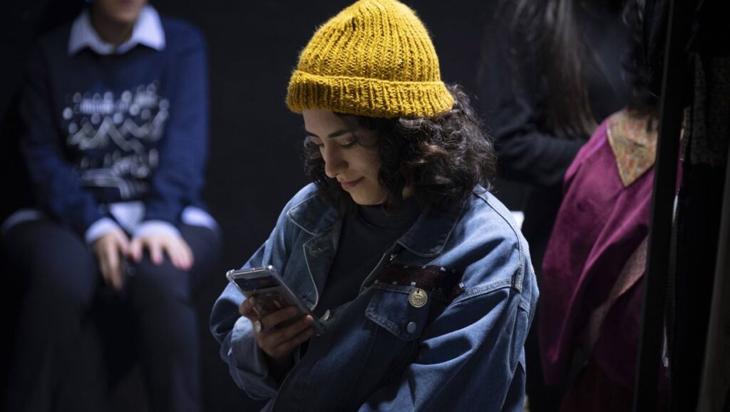 Junge Iranerin in Teheran surft über ihr Handy im Internet