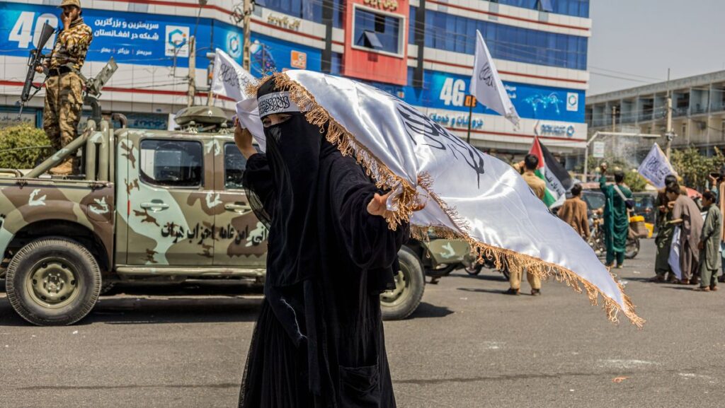 Eine Taliban-Anhängerin mit der Flagge der Islamisten in der afghanischen Stadt Herat
