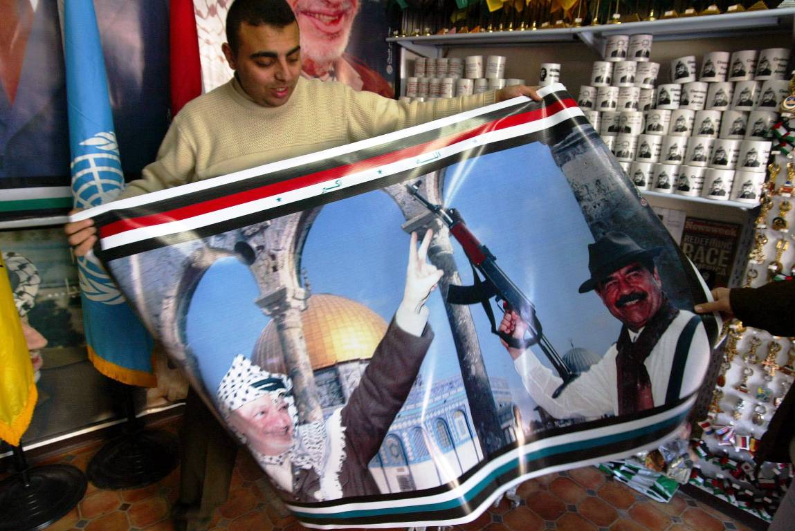 Ein Palästinenser im Gazastreifen verkauft ein Poster von Arafat und Saddam Hussein. (© imago images/UPI Photo)
