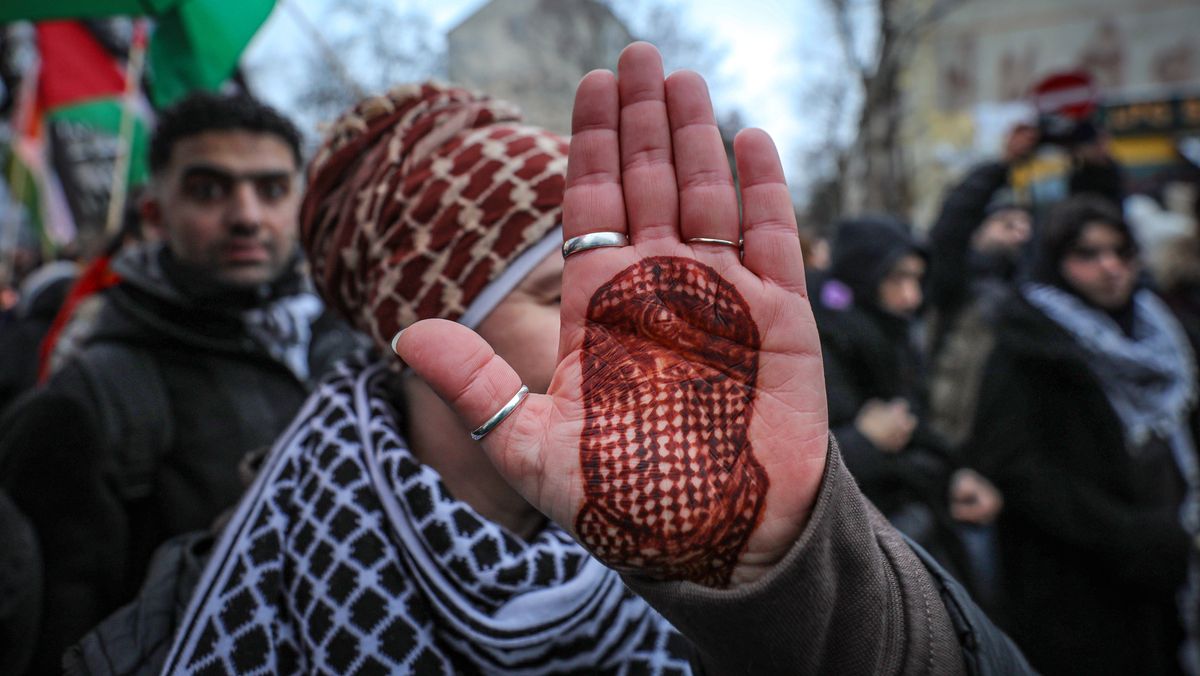 Demonstrantin in Berlin mit Bild des Hama-Militärsprechers Abu Obaida auf ihrer Hand