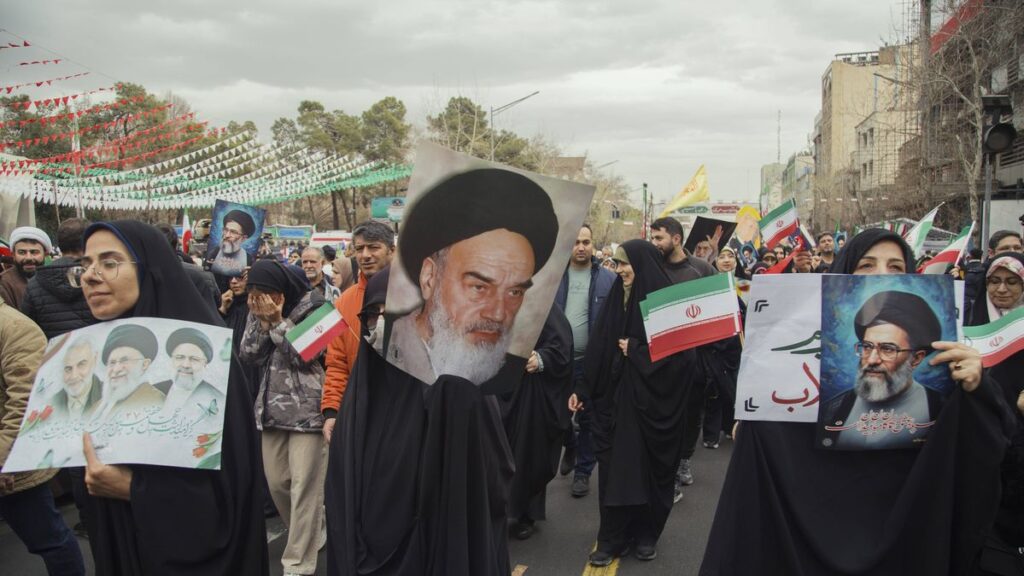Krieg als »göttlicher Segen«: Anhänger des iranischen Regimes mit einem Poster von Revolutionsführer Ruhollah Khomeini Teheran