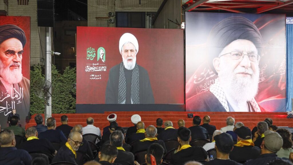 Videoansprache des Hisbollah-Führers Naim Qassem zwischen einem Khomeini- und Khamenei-Poster